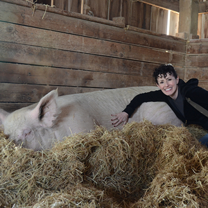 Visitor poses next to pig resident
